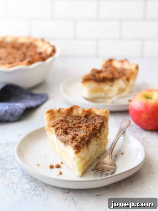 slices of sour cream apple pie on plates with forks