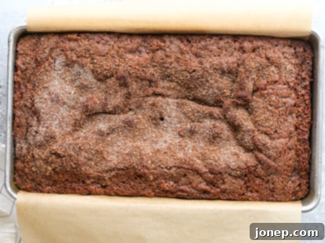 A fresh slice of cinnamon crumble banana bread with a mug of coffee, presented on a wooden board.
