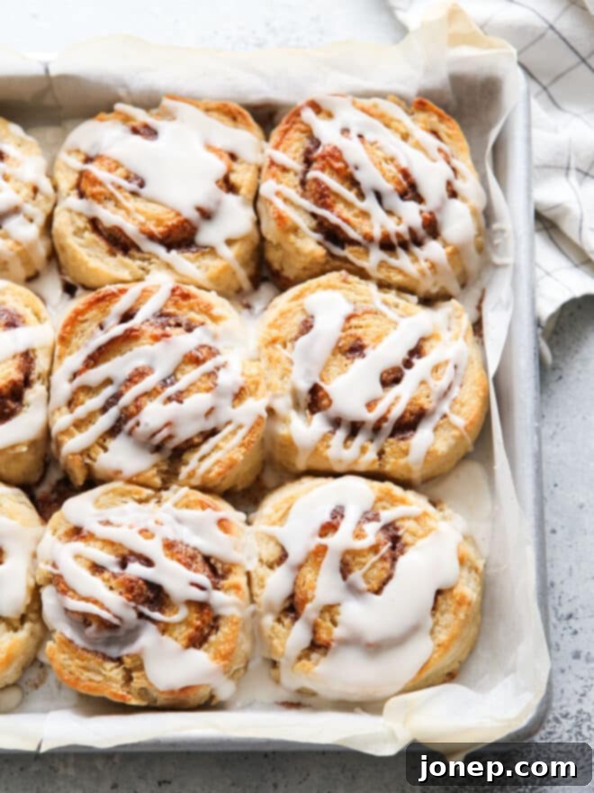 Sweet Cinnamon Swirl Biscuits 2 baked cinnamon roll biscuits in a pan, golden brown and drizzled with icing