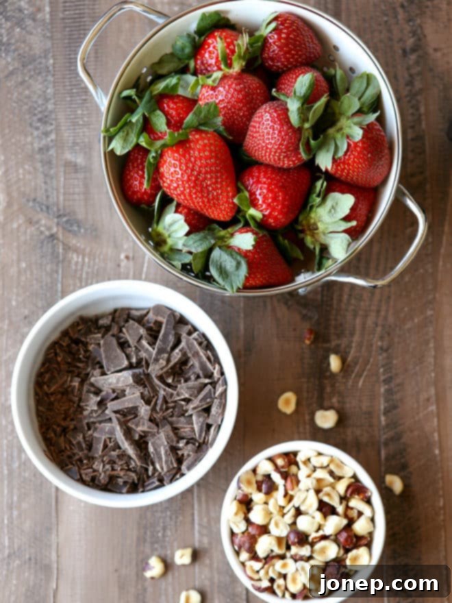 All the essential ingredients for chocolate hazelnut covered strawberries neatly arranged: fresh strawberries, quality chocolate, and whole hazelnuts.