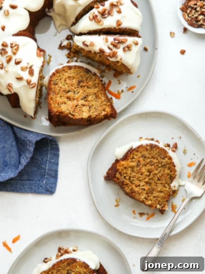 Golden Spiced Carrot Bundt 2 A beautifully decorated carrot bundt cake with cream cheese frosting drizzled over the top, garnished with chopped pecans and coconut.