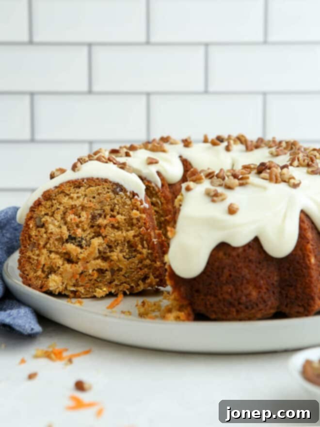 Golden Spiced Carrot Bundt 9 A slice of carrot bundt cake on a white plate, with the rest of the cake in the background.