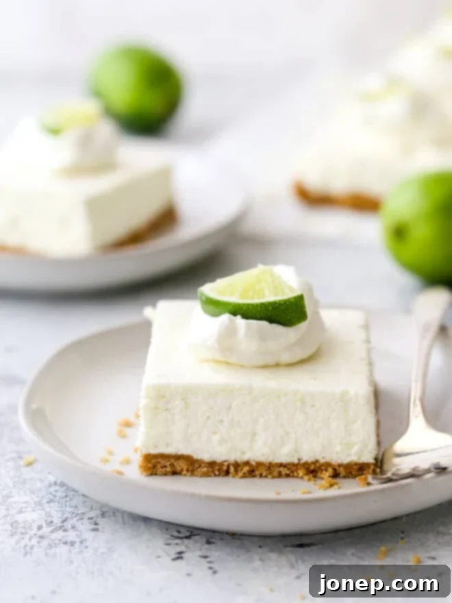 Tangy No-Bake Lime Cheesecake Squares 2 A slice of creamy no-bake lime cheesecake bar on a white plate with a fork, showcasing its vibrant green hue and graham cracker crust.