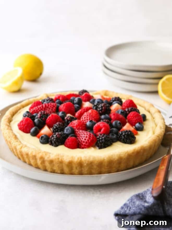 Zesty Lemon Berry Tart 2 A beautifully arranged Lemon Berry Tart on a cooling rack, showcasing its golden crust, pale yellow filling, and vibrant fresh berries.