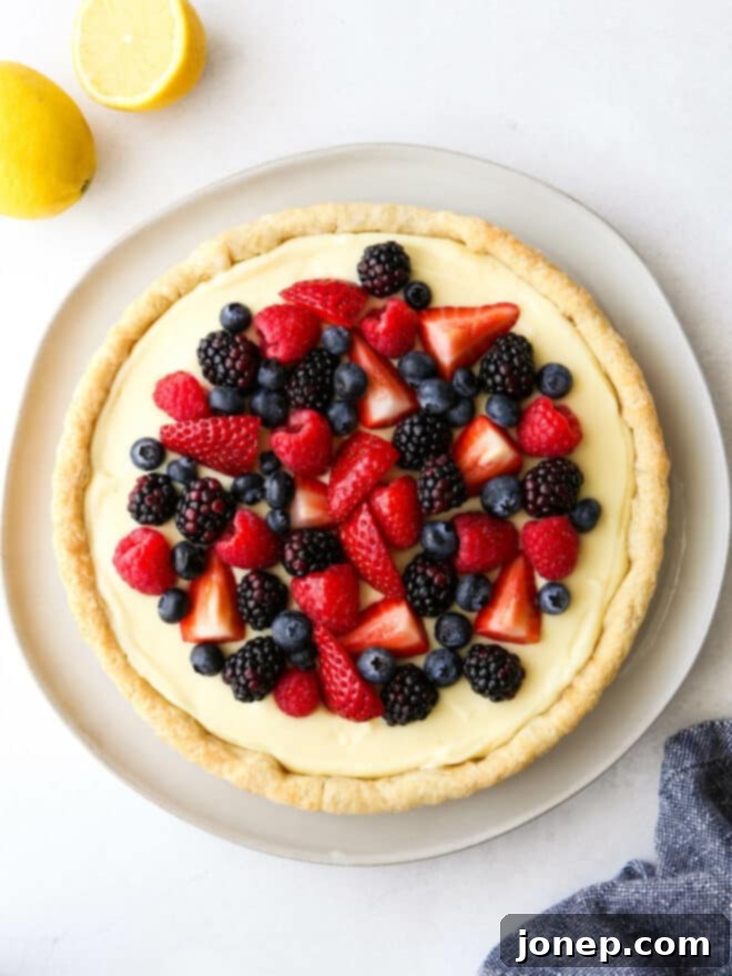 A close-up of a beautifully sliced Lemon Berry Tart, ready to be served, showing its creamy filling and fresh berry topping.
