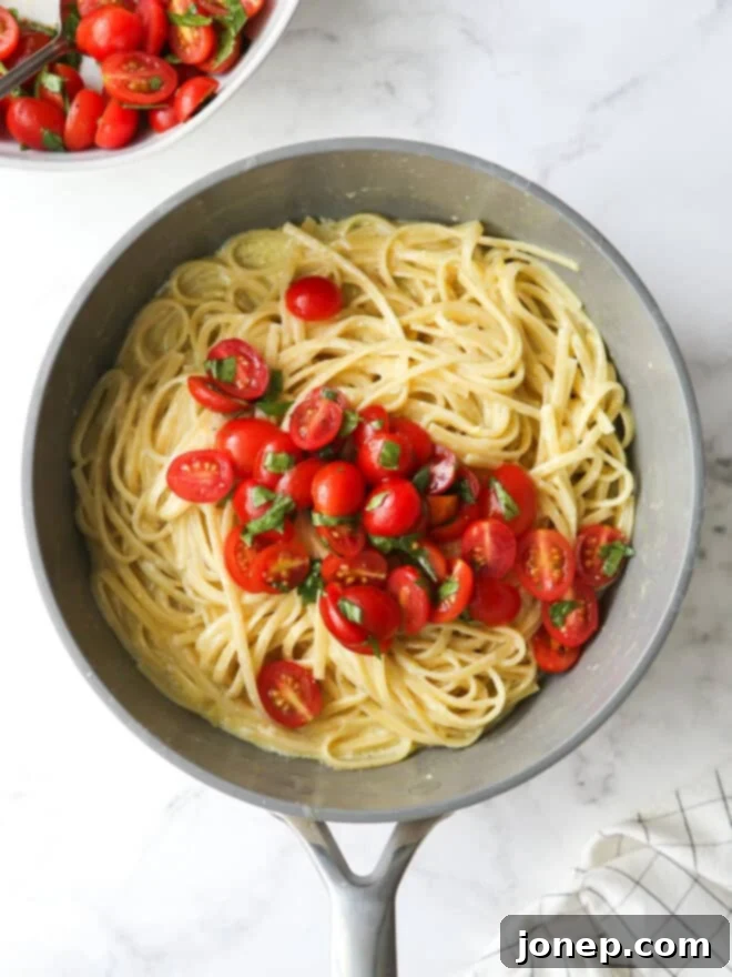 adding marinated tomatoes to pasta in pot