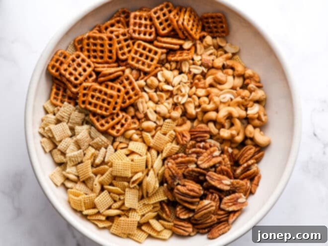 Mixing corn Chex, rice Chex, pretzels, and nuts in a large bowl