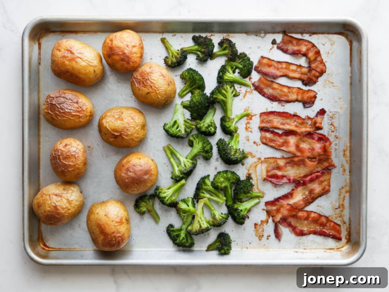 Baked potato sheet pan dinner done and ready for toppings, showcasing golden potatoes, crispy bacon, and vibrant green broccoli.
