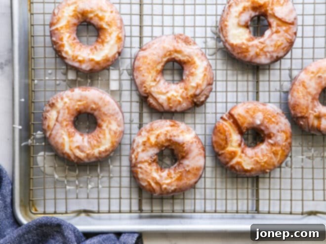 Freshly glazed old-fashioned buttermilk doughnuts resting on a wire rack.