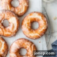Glazed old-fashioned buttermilk doughnuts on a wire rack with a glass of milk.