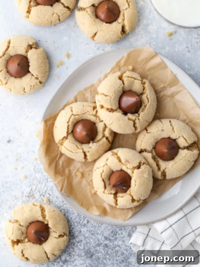 A beautifully arranged platter of freshly baked peanut butter blossom cookies, each topped with a classic Hershey's chocolate kiss, highlighting their nostalgic appeal.