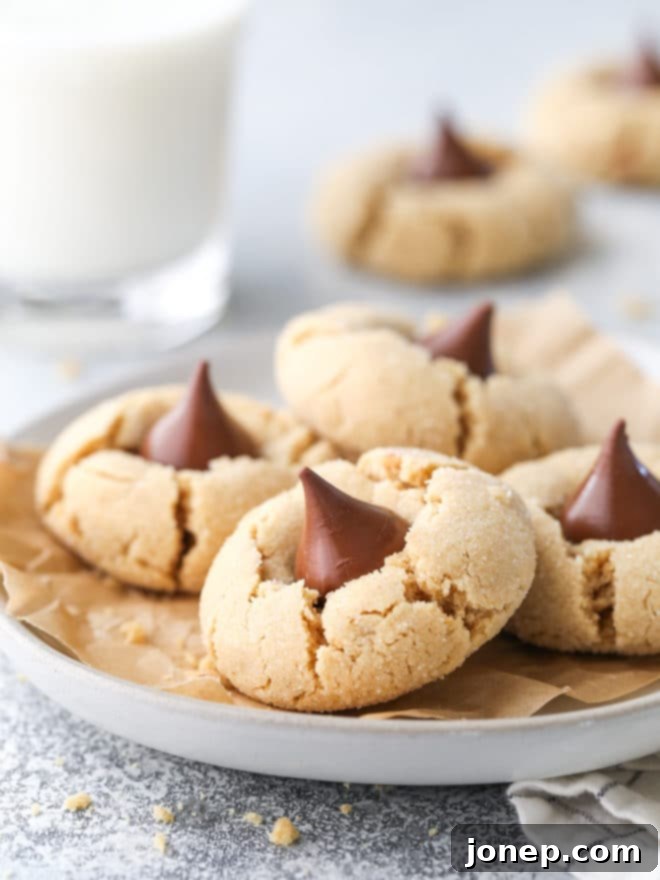 A generous plate full of freshly baked Peanut Butter Blossom cookies, highlighting their nostalgic appeal and delicious chocolate centers