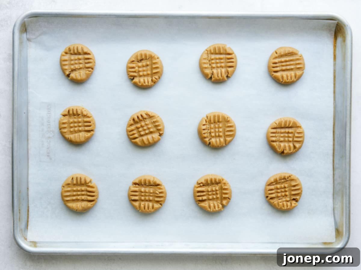 Warm, golden-brown classic peanut butter cookies fresh out of the oven, cooling on a baking sheet.