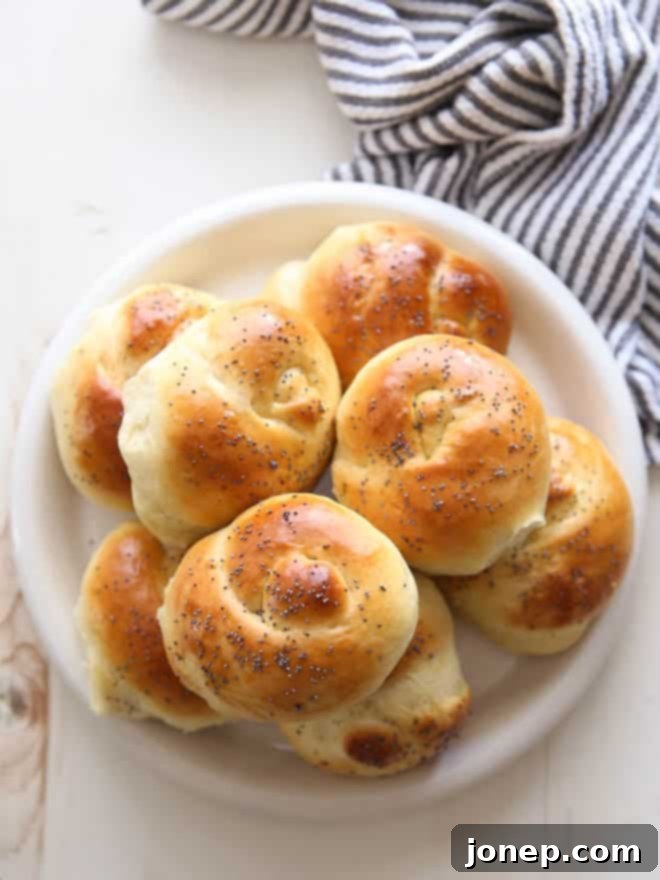 Golden brown Challah rolls cooling on a wire rack, steam gently rising