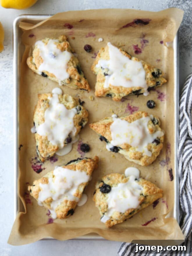 Zesty Lemon Blueberry Scones 2 Freshly baked lemon blueberry scones with a zesty glaze arranged on a rustic wooden board