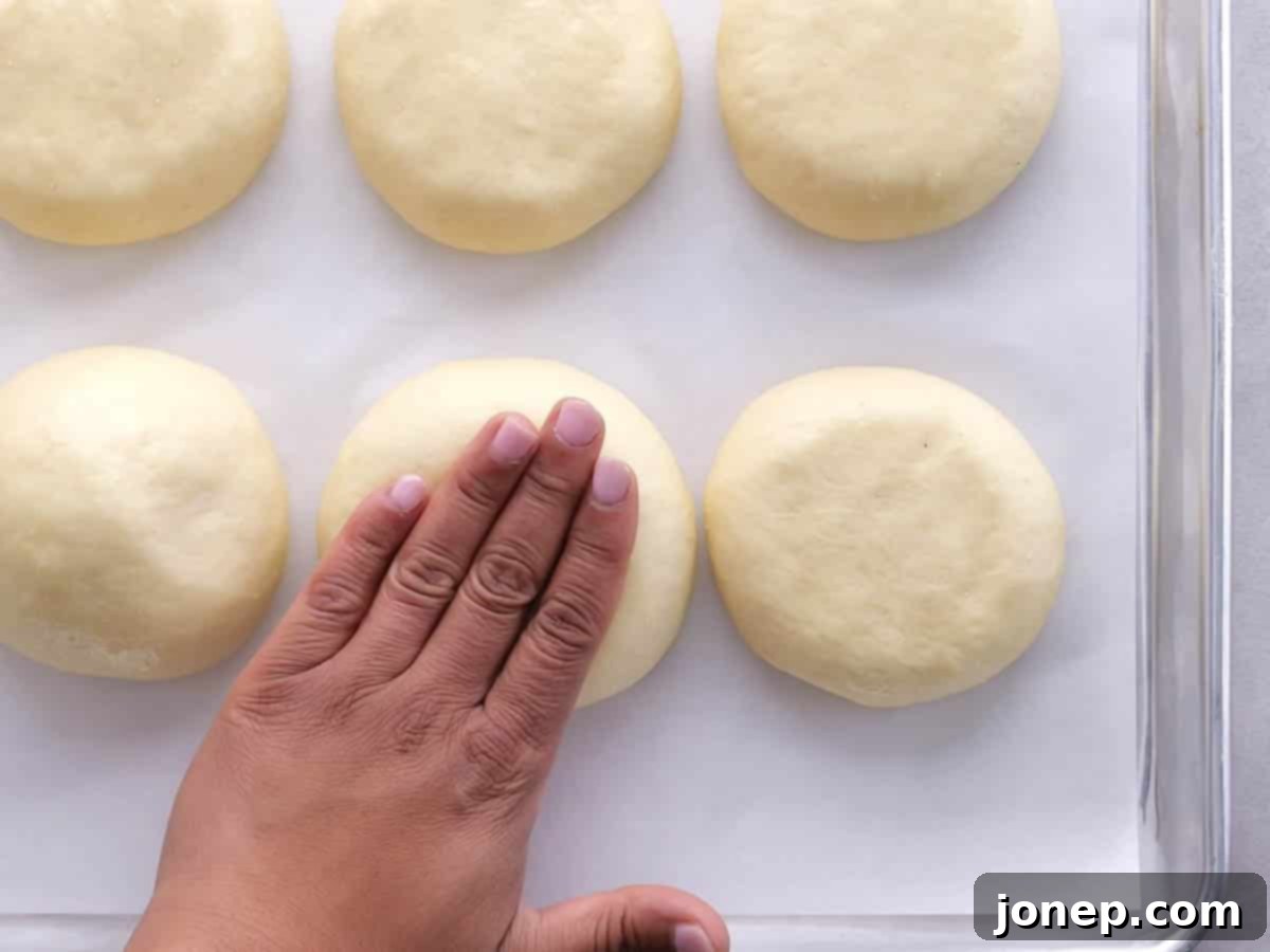 patting the tops of rising burger buns to encourage horizontal expansion