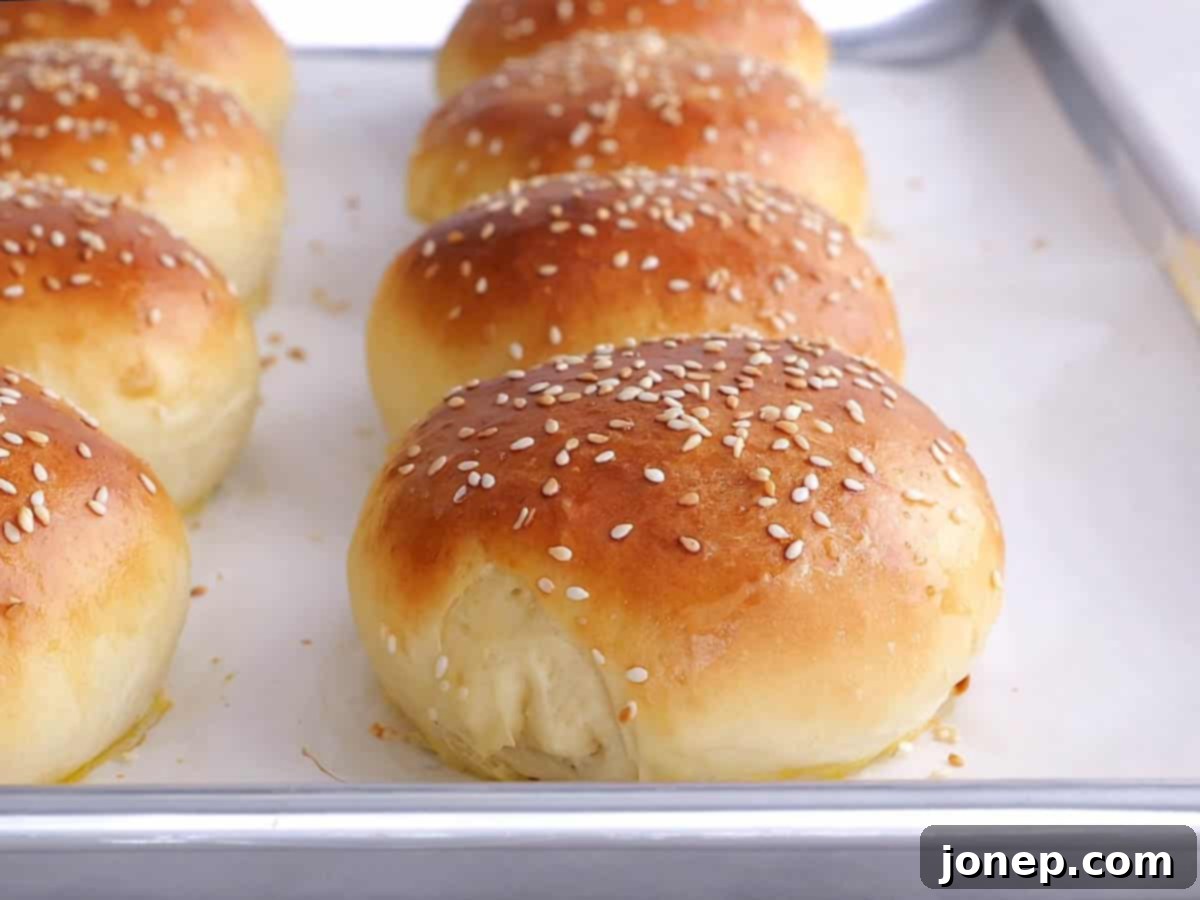 freshly baked golden-brown burger buns on a sheet pan