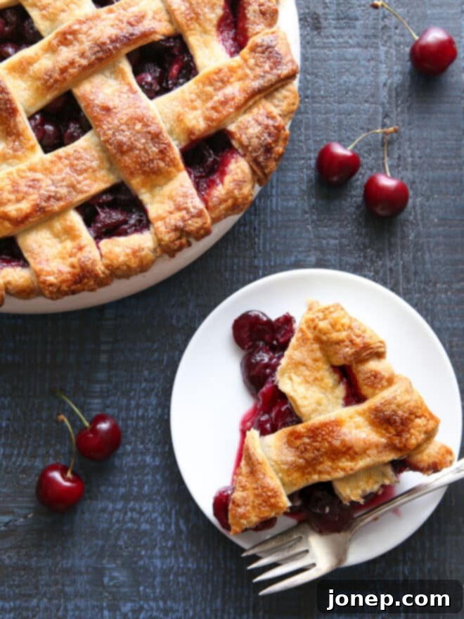 A close-up of a whole sweet cherry pie with a perfectly woven lattice crust, showcasing its golden-brown color and the juicy filling peeking through.