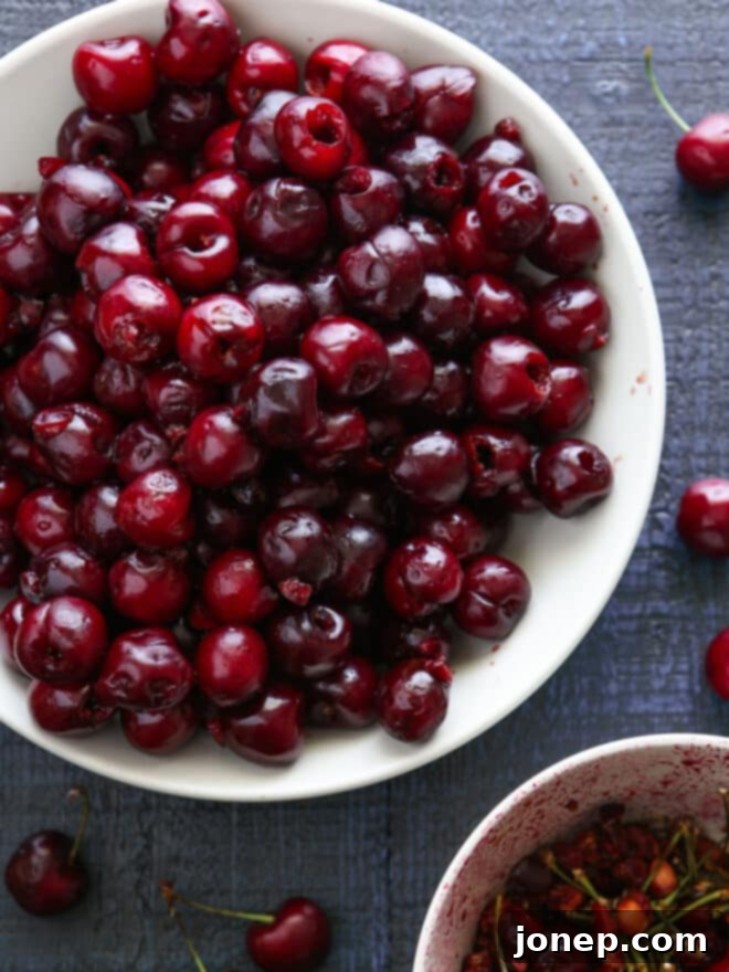 Ingredients for sweet cherry pie laid out on a table, including fresh sweet cherries, sugar, cornstarch, lemon, and almond extract.