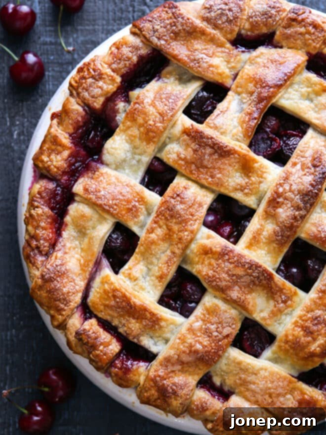 A freshly baked sweet cherry pie, cooled and sliced, showing the vibrant red filling and flaky crust. A perfect summer dessert.
