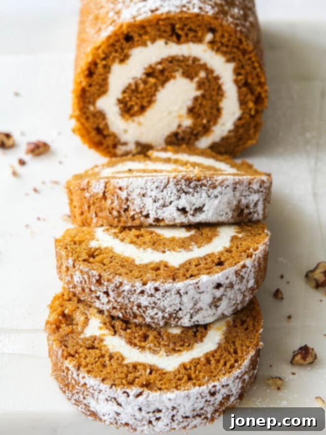 Classic Pumpkin Roll 2 sliced pumpkin roll with candied pecans, showing the beautiful spiral of cake and frosting