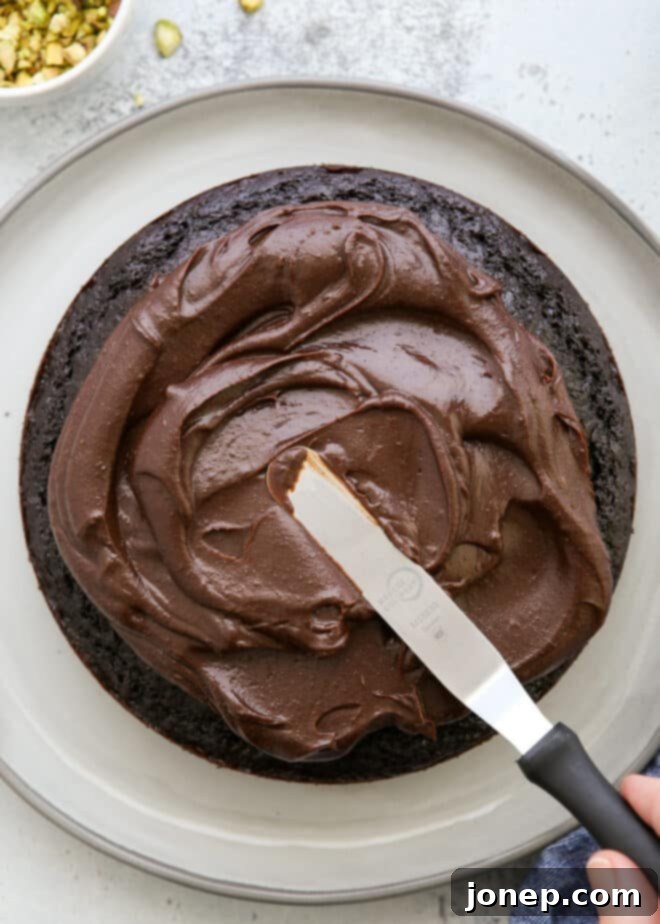 spreading ganache on top of chocolate olive oil cake