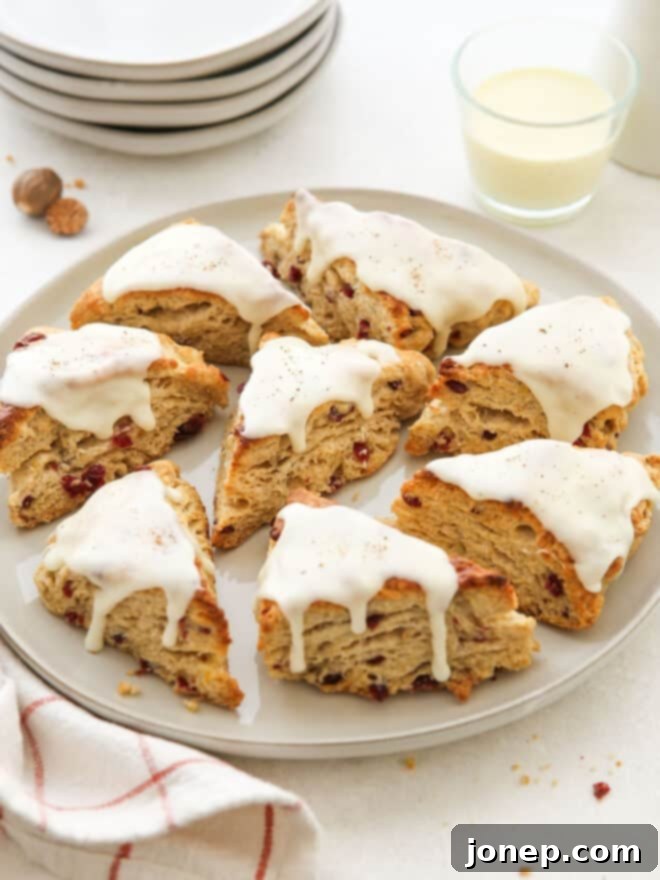 Eggnog Cranberry Scones
Festive Cranberry Eggnog Scones 3 Iced eggnog scones on a platter, accompanied by a glass of eggnog, perfect for a festive holiday breakfast.