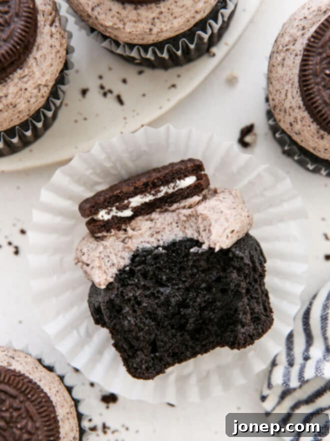 Oreo Bliss Bites 3 A bite taken out of an Oreo cupcake, showcasing the moist chocolate base and creamy Oreo frosting.