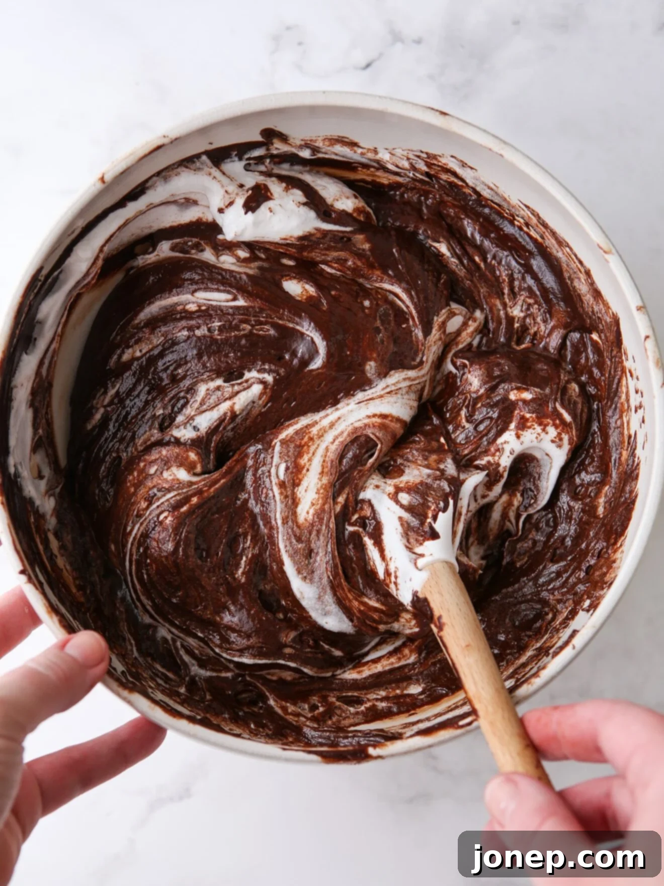 Image of ingredients being folded together in a bowl, hinting at the creation of a delicious chocolate dessert.