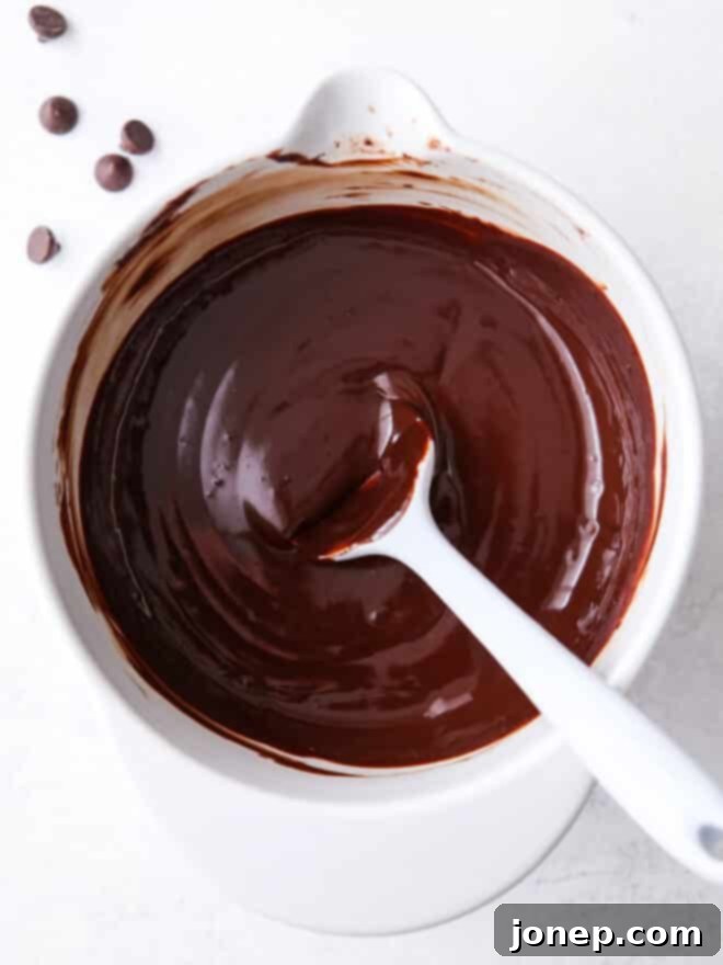 A close-up of luscious chocolate ganache in a bowl, ready to be used in a variety of decadent desserts.