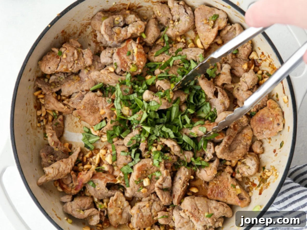 Adding garlic, green onions, and chilies to the Thai lemongrass pork stir-fry.